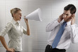 Foto: Businesswoman screaming through megaphone, businessman covering his ears Businesswoman screaming through megaphone, businessman covering his ears