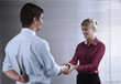 Foto: Businessman and businesswoman shaking hands, businessman hiding knife behind his back Businessman and businesswoman shaking hands, businessman hiding knife behind his back