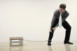 Businessman with box of loans chained to his leg