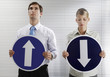 Foto: Businessman and businesswoman holding arrow signs showing different directions Businessman and businesswoman holding arrow signs showing different directions