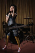 Young woman with electric guitar singing in recording studio