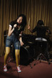 Young woman singing, man playing drums in the background