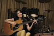 Young woman smiling while playing guitar