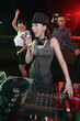Woman spinning turntable while singing with people dancing in the background