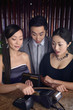 Woman swiping credit card, her friends watching her