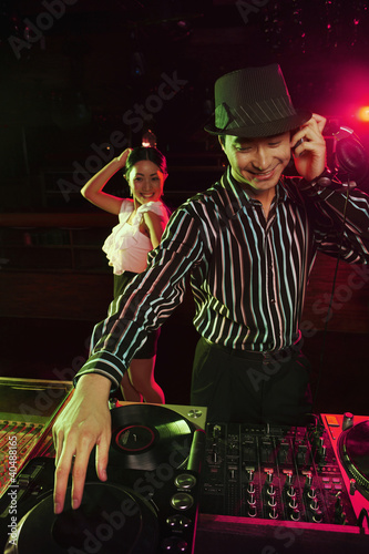 Foto: Man spinning some tunes on turntable with woman dancing in the background Man spinning some tunes on turntable with woman dancing in the background