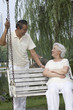 Foto: Senior woman talking to senior man while sitting on a swing Senior woman talking to senior man while sitting on a swing