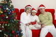 Foto: Boy holding heart shaped gift box, senior man and senior woman beside him Boy holding heart shaped gift box, senior man and senior woman beside him