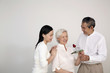 Senior man giving senior woman a stalk of rose, woman smiling while watching