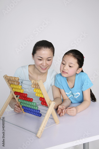 Photo: Woman teaching girl how to use the abacus Woman teaching girl how to use the abacus