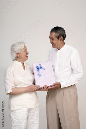 Photo: Senior woman receiving gift from senior man Senior woman receiving gift from senior man