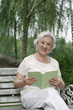 Foto: Senior woman reading book while sitting on a swing Senior woman reading book while sitting on a swing