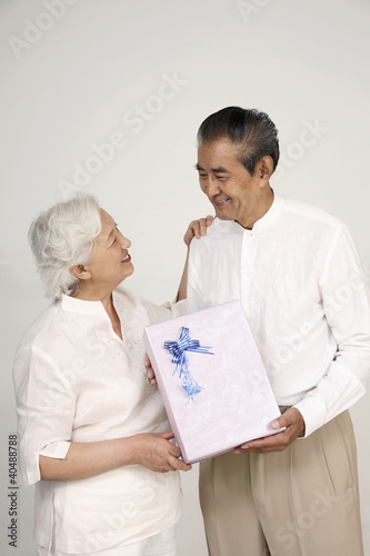 Photo: Senior man receiving gift from senior woman Senior man receiving gift from senior woman