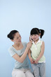 Woman holding cellphone at girl's ear