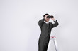 Businessman on ladder, looking through binoculars