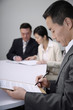 Businessman reading document with other business people in the background