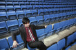 Businessman sitting on stadium seat, contemplating