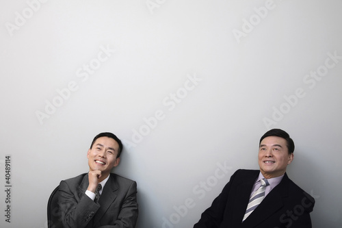Foto: Businessmen smiling while contemplating Businessmen smiling while contemplating