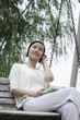 Foto: Woman listening to music on headphones while reading book Woman listening to music on headphones while reading book