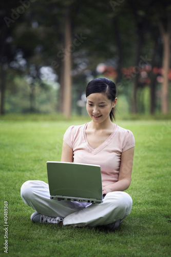Photo: Woman using laptop in the park Woman using laptop in the park
