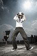 Foto: Young woman posing, young man making a breakdance move in the background Young woman posing, young man making a breakdance move in the background