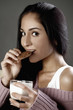 Foto: Woman biting on a cookie and holding a glass of milk Woman biting on a cookie and holding a glass of milk