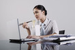 Foto: Businesswoman eating instant noodle while using laptop Businesswoman eating instant noodle while using laptop