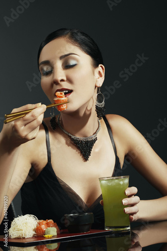 Foto: Woman eating salmon sashimi with cold green tea Woman eating salmon sashimi with cold green tea