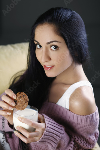 Photo: Woman holding cookie and a glass of milk Woman holding cookie and a glass of milk