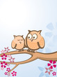 Two owls sitting in a tree with flowers