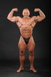 Undressed tanned smiling bodybuilder demonstrates his arm muscle
