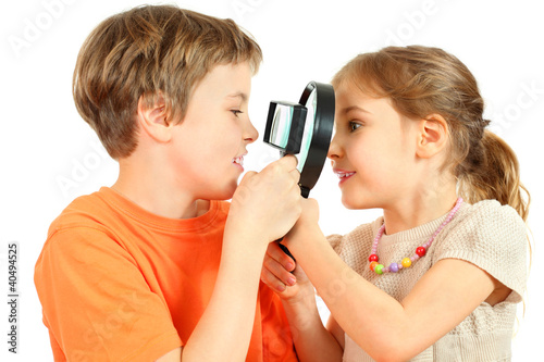 Photo: Brother and sister look at each other through magnifying glasses Brother and sister look at each other through magnifying glasses
