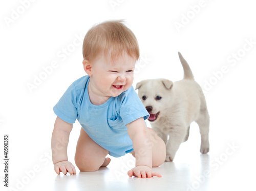 Photo: cute child playing and crawling away a puppy, puppy following cute child playing and crawling away a puppy, puppy following