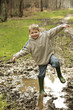 Boy playing in mud puddle