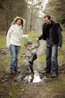 Boy playing in mud puddle with his parents
