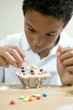 Boy decorating a small cake