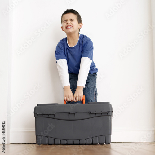 Photo: Boy trying to carry up a toolbox Boy trying to carry up a toolbox