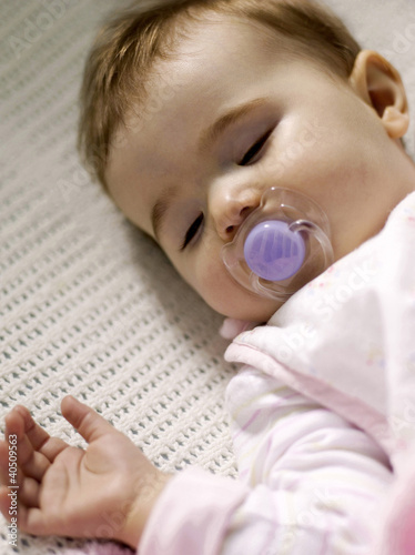 Foto: Baby girl with pacifier sleeping in the crib Baby girl with pacifier sleeping in the crib