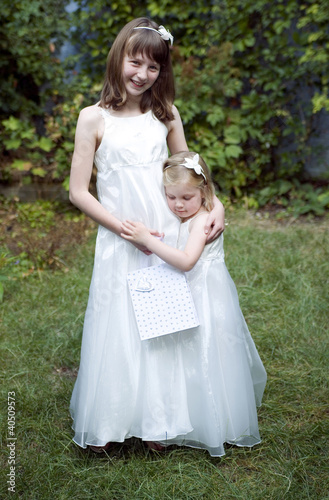 Photo: Sisters wearing white dress embracing Sisters wearing white dress embracing