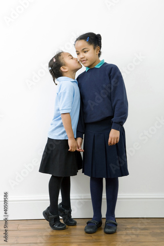 Photo: Girl whispering into her sister's ear Girl whispering into her sister's ear