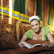 Woman lying on the couch reading book