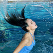 Woman emerging from under the water splashing her hair