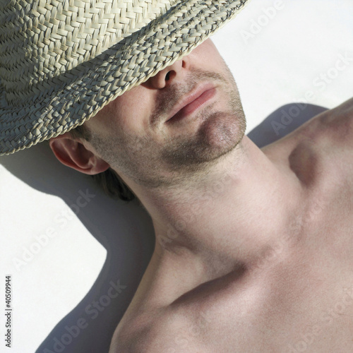 Foto: Man relaxing with straw hat covering his eyes Man relaxing with straw hat covering his eyes