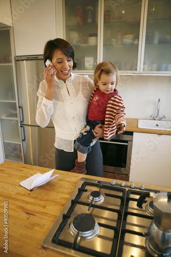 Foto: Mother carrying daughter while talking on the phone Mother carrying daughter while talking on the phone