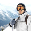 Man in warm clothing and ski goggles holding snowboard