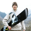 Man in warm clothing holding snowboard