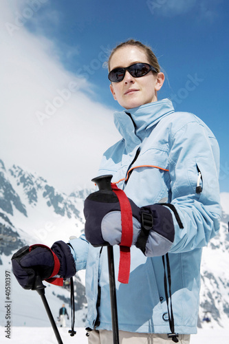Photo: Woman with sunglasses holding on skiing poles Woman with sunglasses holding on skiing poles