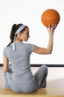 Woman sitting on bench holding up basketball