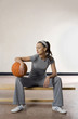 Woman sitting on bench with a basketball