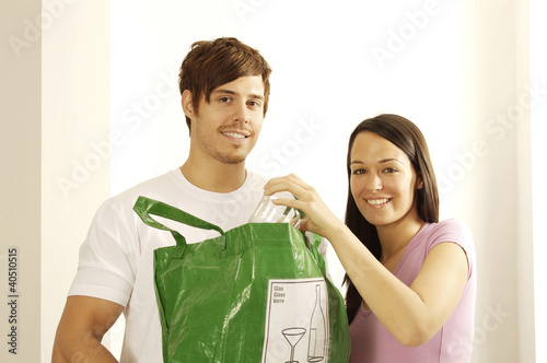 Photo: Man and woman with glass and plastic bag for recycling Man and woman with glass and plastic bag for recycling